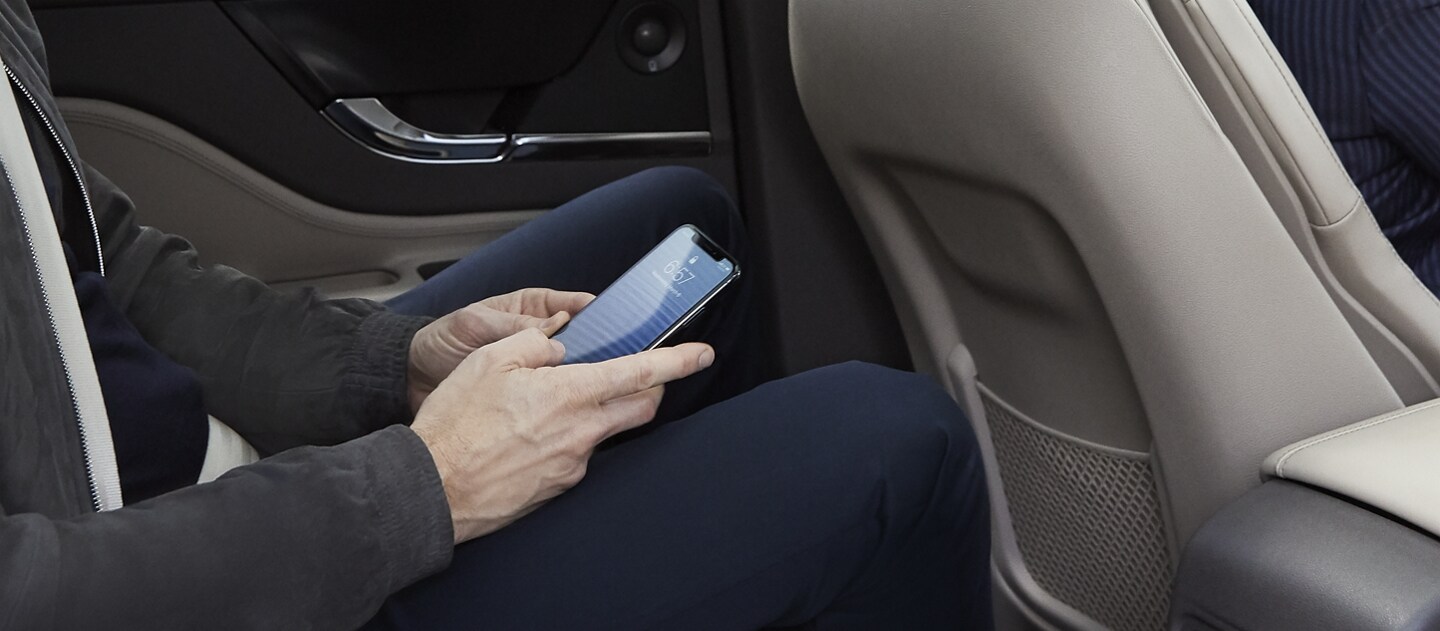 Un pasajero en el asiento trasero de una SUV Lincoln Corsair® 2023 usando su smartphone