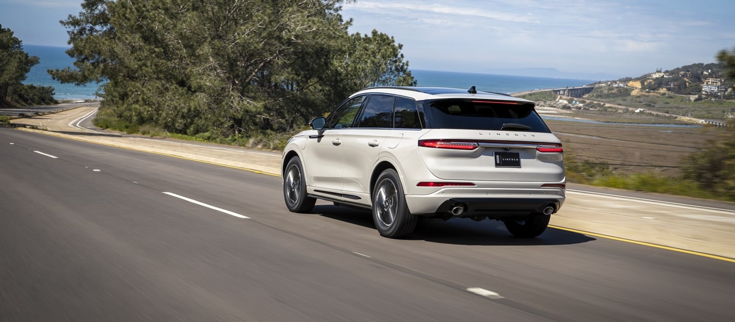 Un modelo Lincoln Corsair® Grand Touring 2023 andando junto a un paisaje escénico de un océano azul que se desvanece en el horizonte