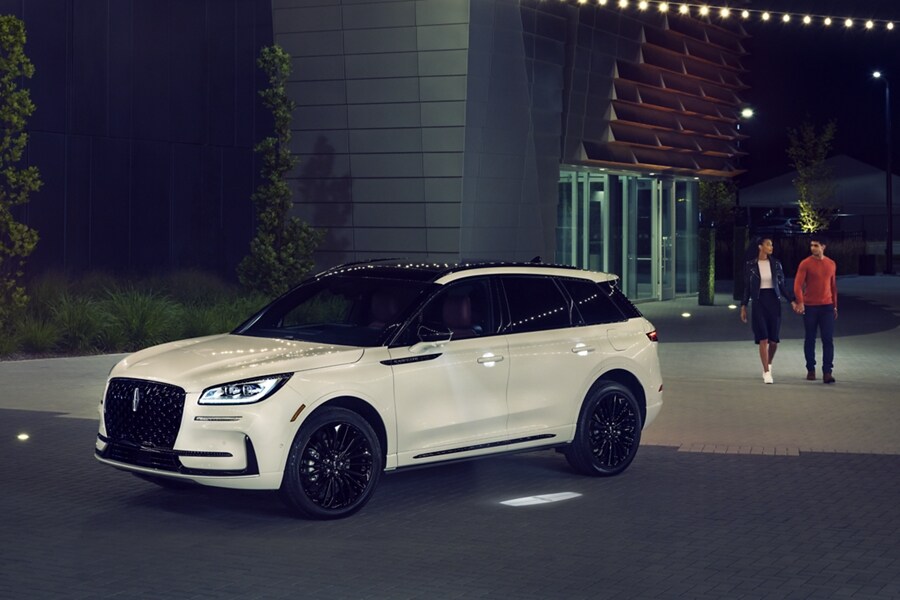 Dos personas acercándose a una SUV Lincoln Corsair® 2023 en una noche, recibida por el suave brillo de Lincoln Embrace