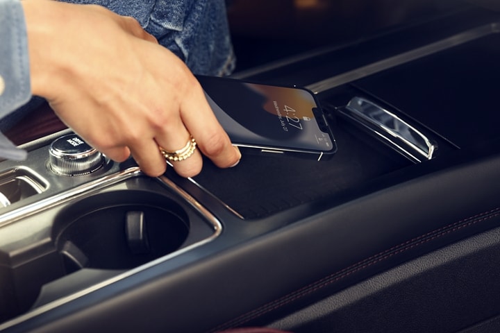 A smartphone device is being placed on to the available wireless charging pad of a 2023 Lincoln Corsair® SUV