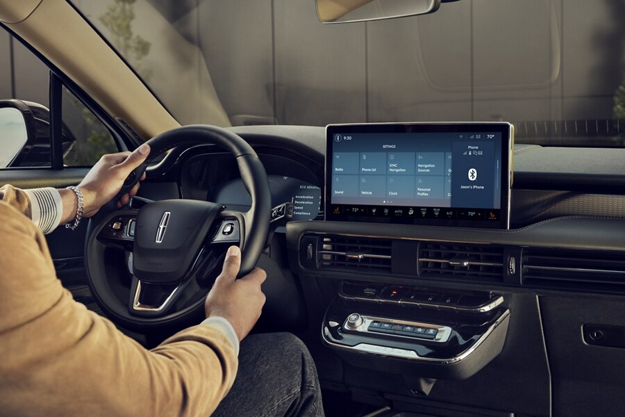 Se muestra una persona sentada en el asiento del conductor de una SUV Corsair® 2023 que está ajustando su configuración de perfil