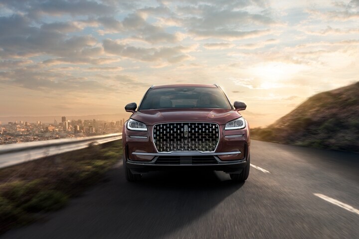 A 2023 Lincoln Corsair® SUV is being driven on a sun-drenched road