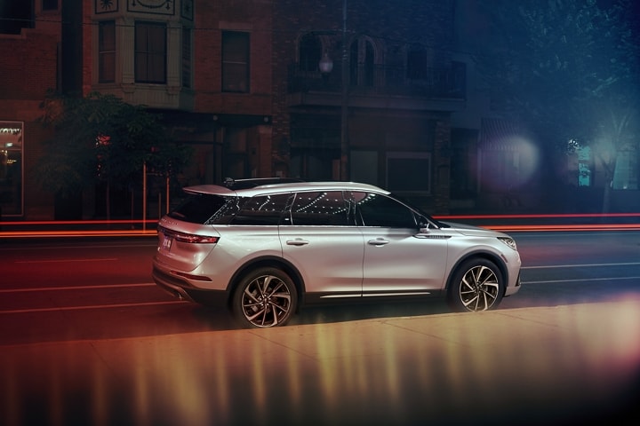 A 2023 Lincoln Corsair® SUV is parked near a theatre at night as the bright lights of a marquee dance across the exterior