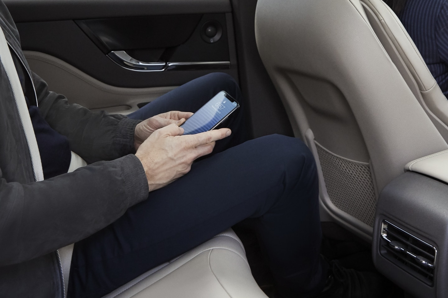 A rear-seat passenger of a 2024 Lincoln Corsair® SUV uses his smartphone