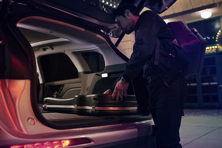 Un músico desliza el estuche de su guitarra en el espacio de carga de una SUV Lincoln Corsair® 2024 con los asientos traseros plegados