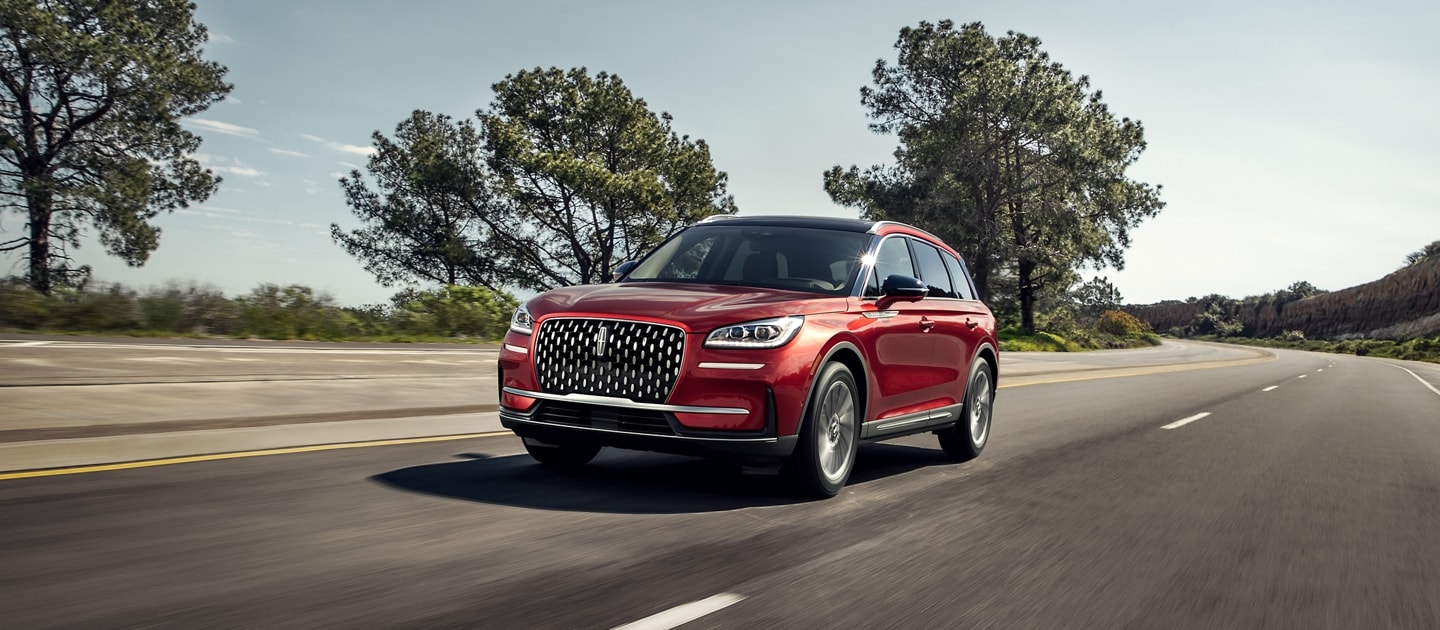 A 2024 Lincoln Corsair® SUV is being driven on a tree-lined road