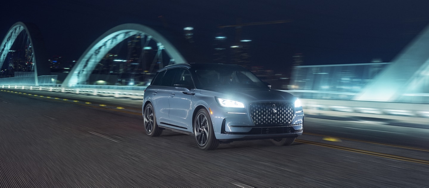 The 2024 Lincoln Corsair® SUV drives across an illuminated bridge at night