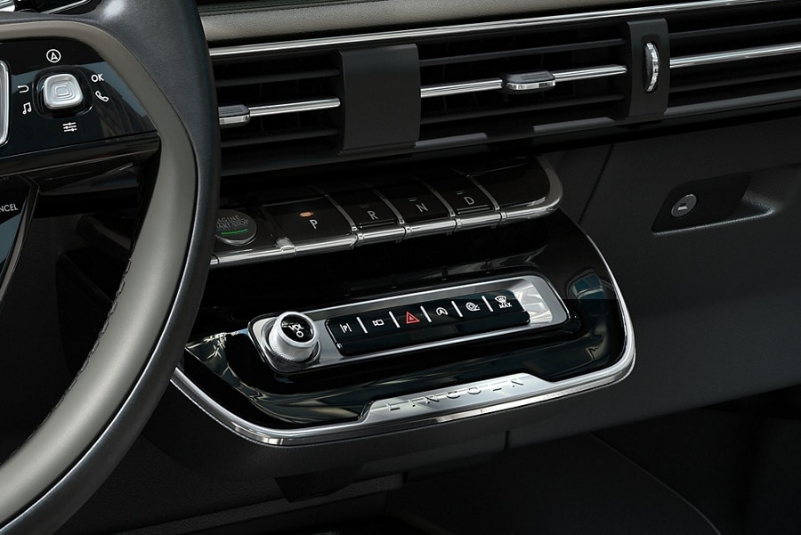The park button on the elegant piano key shifter is lit up and engaged as light dances off chrome accents and design lines