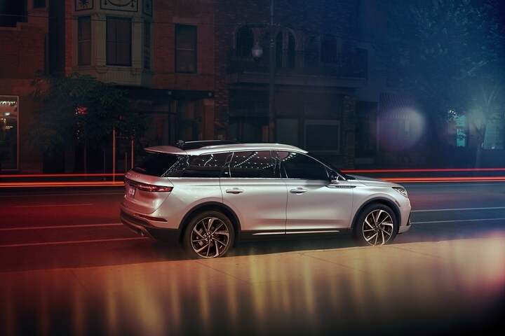 Una SUV Lincoln Corsair® 2024 está estacionada cerca de un teatro de noche, mientras las luces brillantes de una marquesina danzan en el exterior