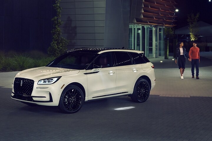 A couple approaches a 2025 Lincoln Corsair® SUV as the Lincoln Embrace illumination guides the way