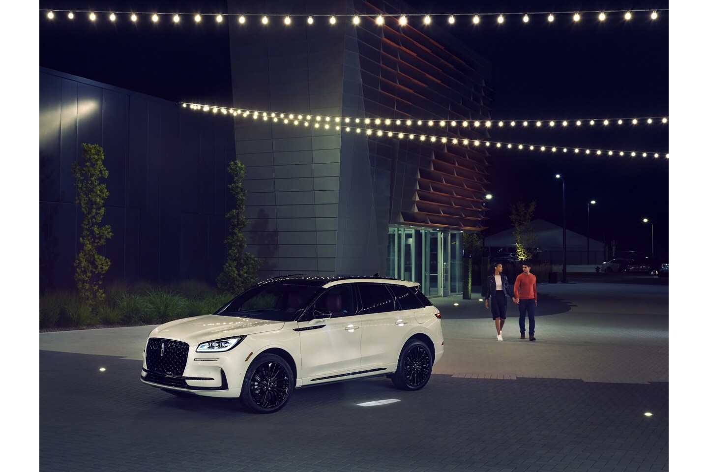 A couple approaches a 2025 Lincoln Corsair® Reserve model as the Lincoln Embrace illumination guides the way