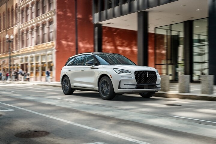 A 2025 Lincoln Corsair® Reserve model with the Available Jet Appearance Package is being driven in a city setting.