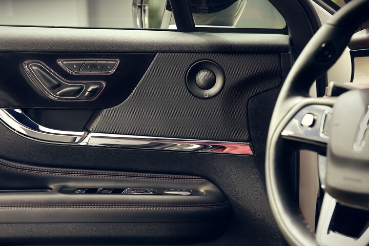 A mid-range speaker of the available 14-speaker Revel Audio System is shown in the front driver's door panel