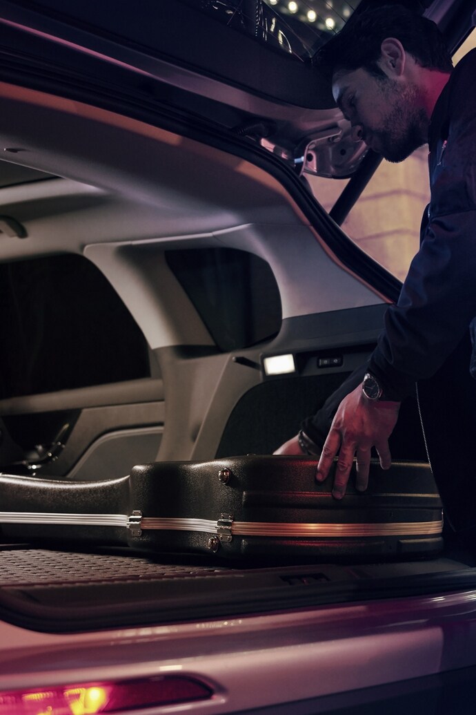 A man putting a guitar case in the trunk