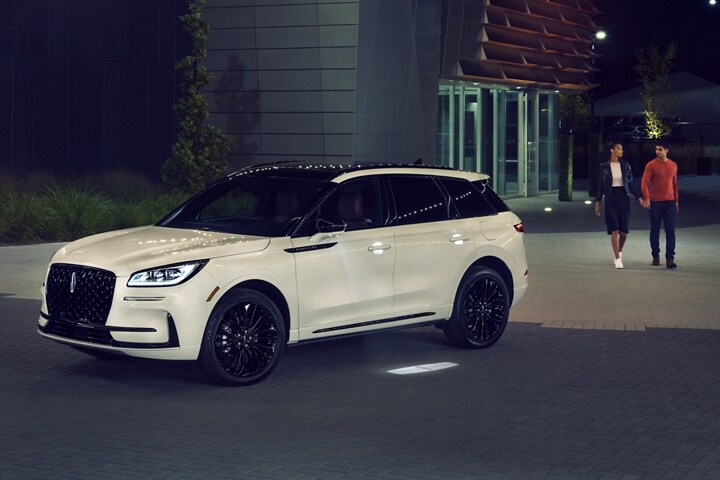 A couple approaches a 2026 Lincoln Corsair® SUV as the Lincoln Embrace illumination guides the way