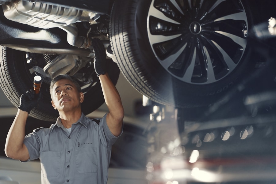 A Lincoln service technician is inspecting under the hood of a Lincoln vehicle