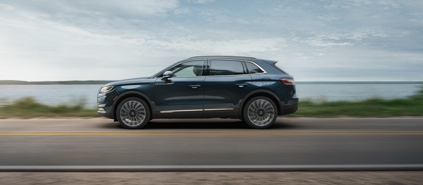Una SUV Lincoln Nautilus® 2023 que se desplaza por una carretera cerca de un lago