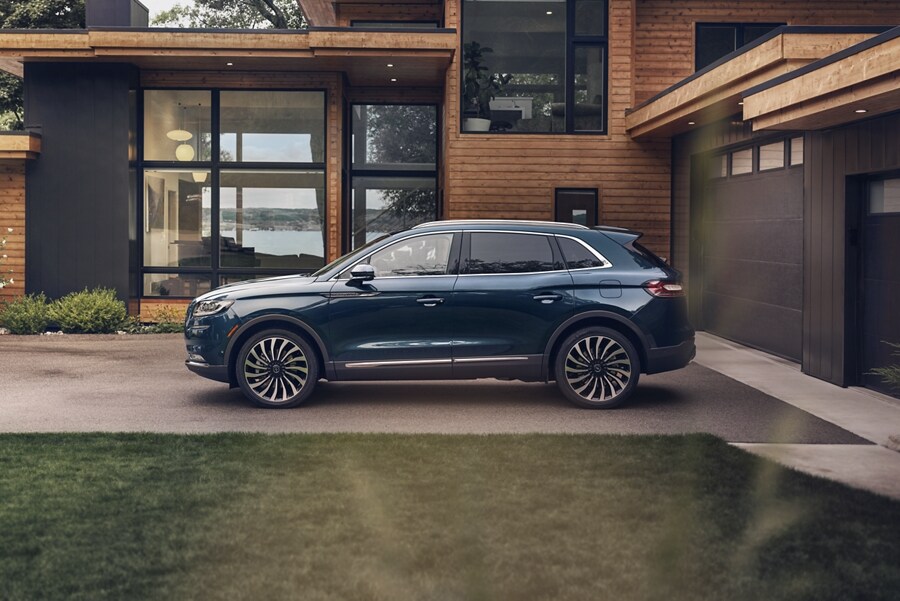 A 2023 Lincoln Black Label Nautilus® SUV is parked outside a modern lake house