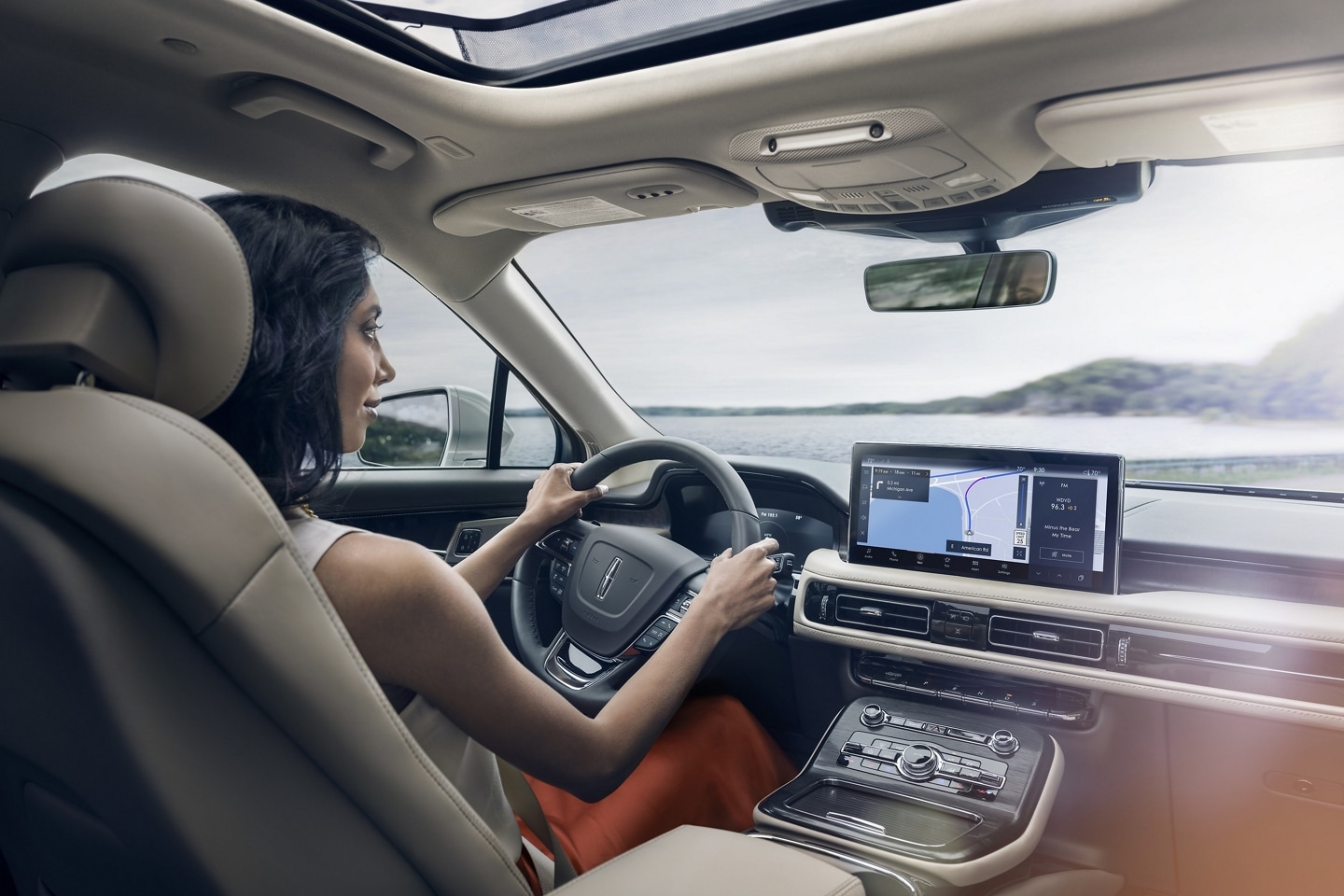 Una mujer conduce una SUV Lincoln Nautilus® 2023 mientras la aplicación de navegación en la pantalla táctil central guía su curso
