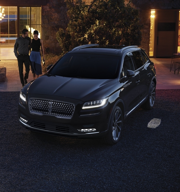 A 2023 Lincoln Nautilus® SUV illuminates as a couple approaches the vehicle