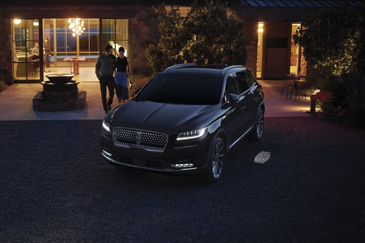 Una pareja se aproxima de noche a una SUV Lincoln Nautilus® 2023