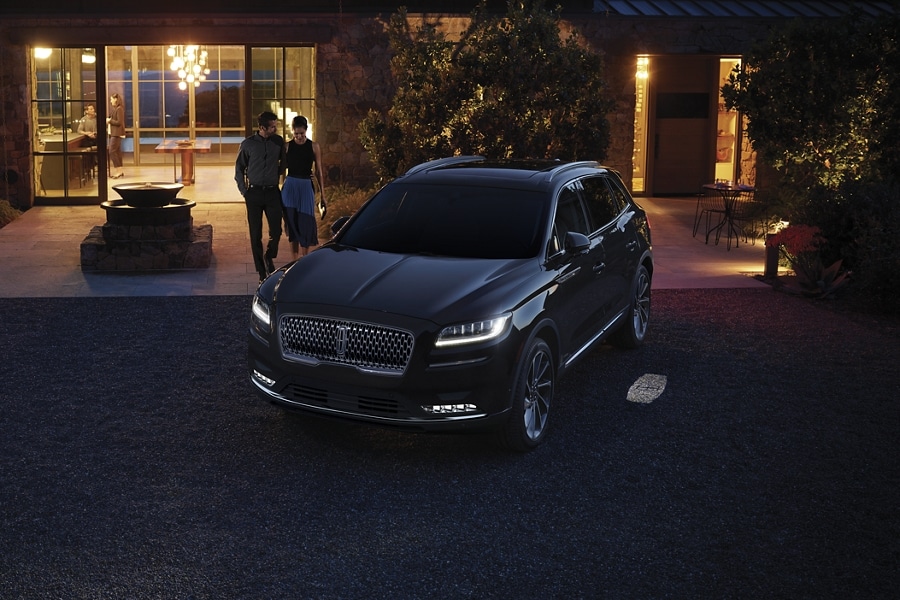 A couple approach a 2023 Lincoln Nautilus® SUV as the Lincoln embrace lighting sequence illuminates the way