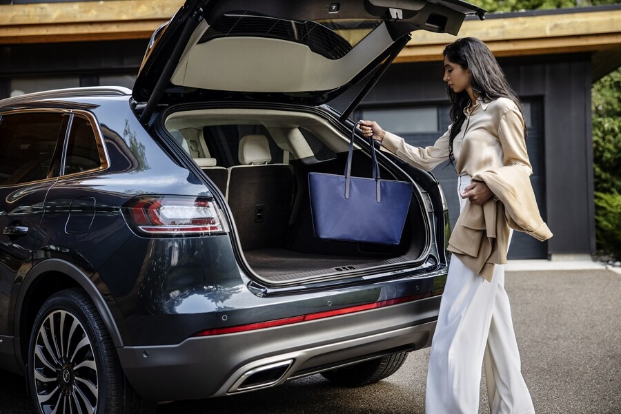 A person uses the hands-free liftgate on the 2023 Lincoln Black Label Nautilus® SUV and places a bag in the rear cargo area