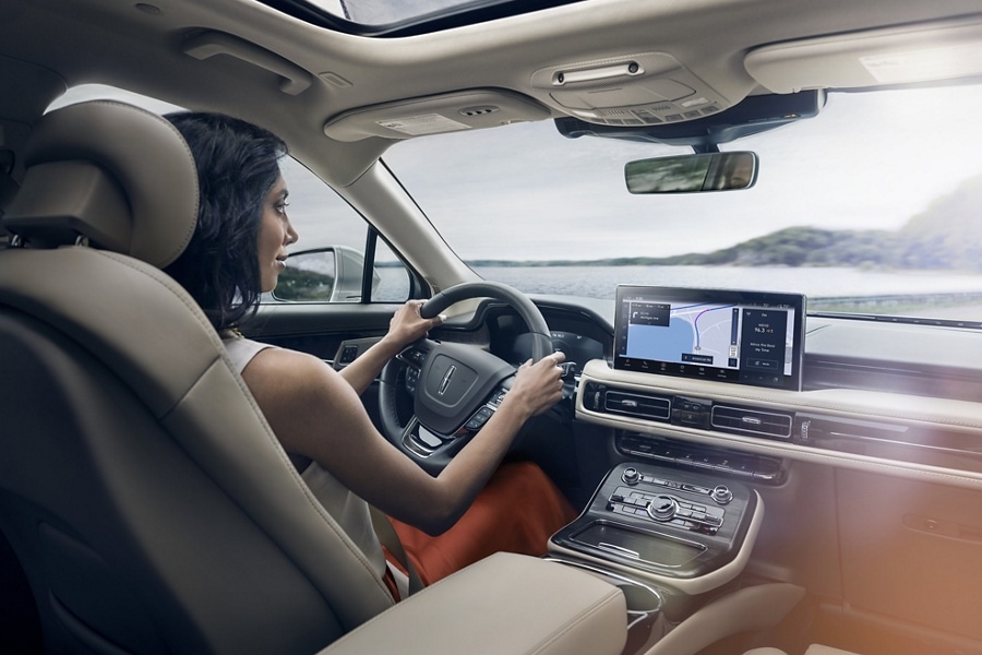A woman is driving a 2023 Lincoln Nautilus® SUV as the navigation application on the center touchscreen guides her course