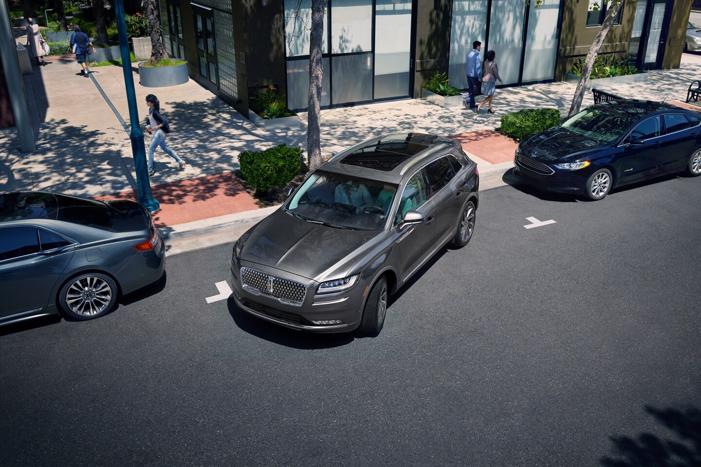 A 2023 Lincoln Nautilus® SUV is shown being parallel parked in a quaint city shopping area