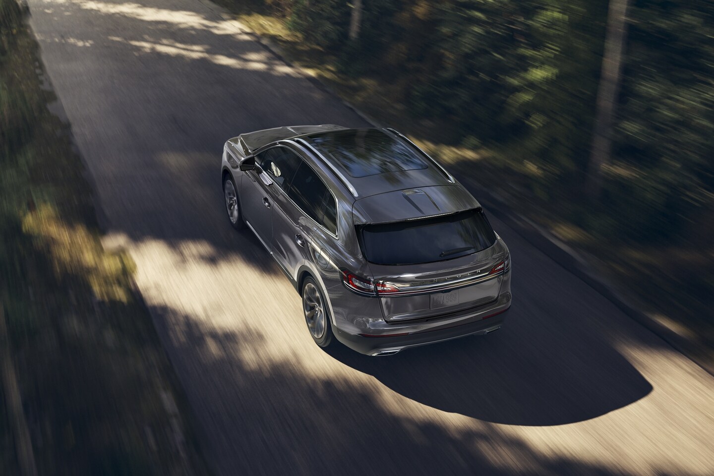Se muestra una SUV Lincoln Nautilus® 2023 en una carretera bordeada de árboles para demostrar el rendimiento del motor doble turbocargado​​​​​​​.