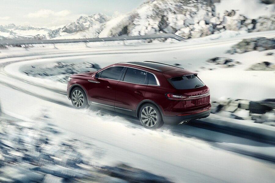 Se muestra una SUV Lincoln Nautilus®​​​​​​​ 2023 circulando por una carretera cubierta de nieve, con una curva pronunciada por delante