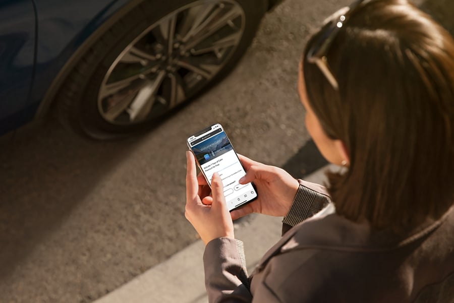 A woman is opening the Calm app on her phone as she approaches her Lincoln vehicle