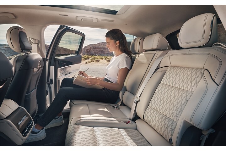 A woman journals in the second row of a Lincoln Black Label™ Nautilus® SUV