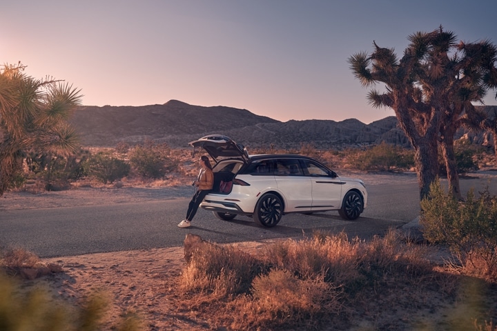 A woman sits on the edge of the rear cargo area of a 2026 Lincoln Nautilus® SUV