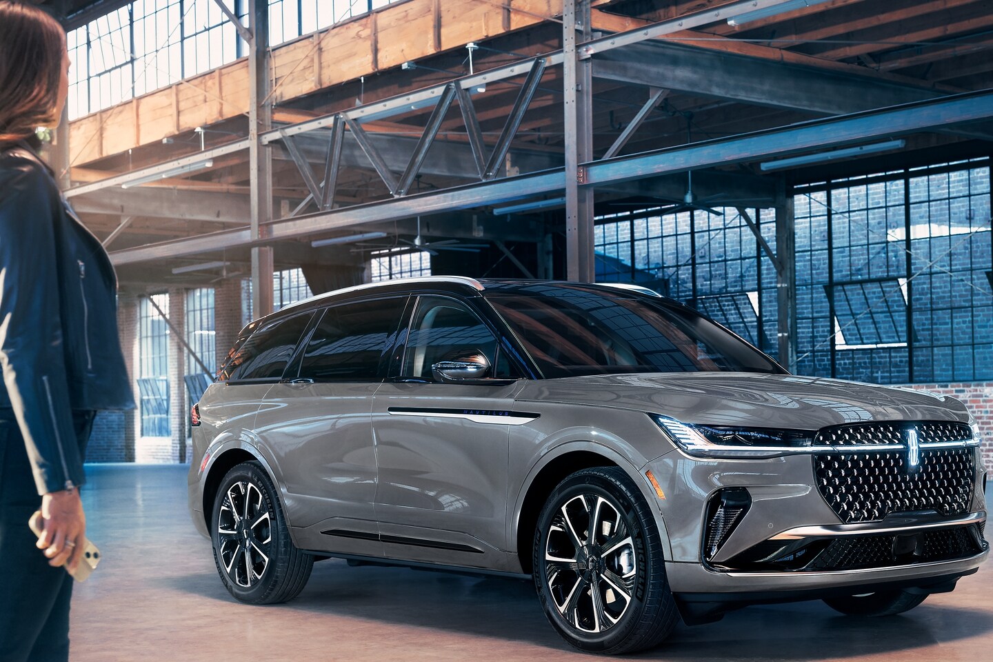 A woman approaches a 2026 Lincoln Nautilus® SUV while holding a mobile phone