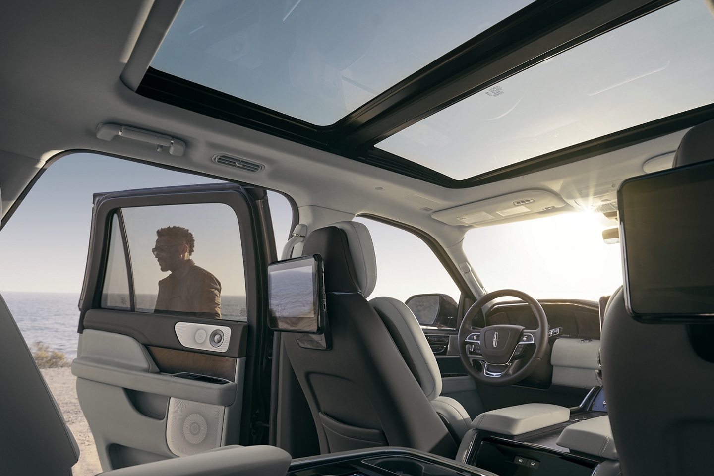 Blue skies are seen through the expansive panoramic Vista Roof® as sunlight illuminates the broad cabin with a warm glow.