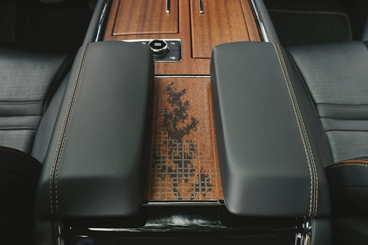Deep-polished wood featuring natural grain patterns adorns the spacious three-chambered center front console.