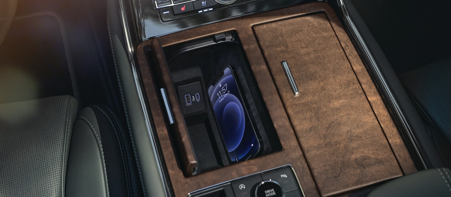 Un smartphone cargándose en la base de carga inalámbrica dentro de un cubículo en la consola central de una SUV Lincoln Navigator® 2023.