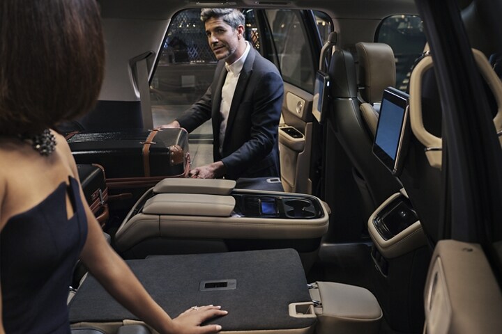 A man is pulling a suitcase out of the folded-flat second row of a 2023 Lincoln Black Label Navigator® SUV.