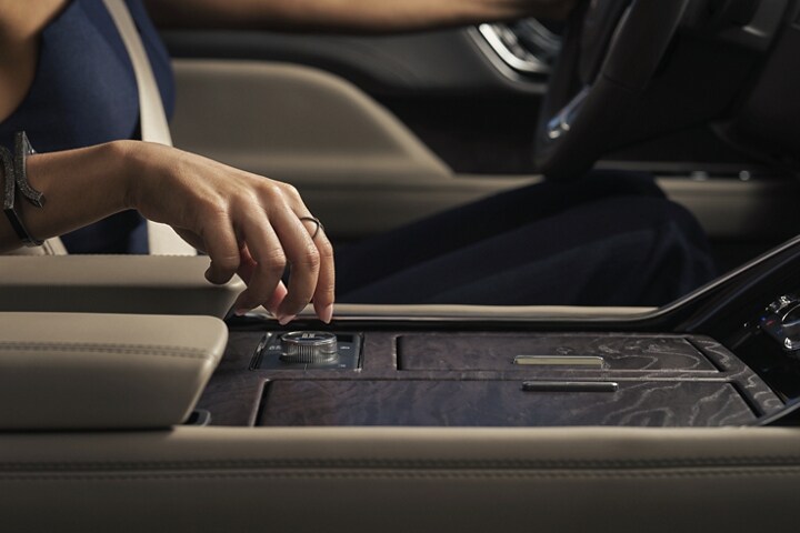 A hand is about to turn the Lincoln Drive Modes knob in the center console.