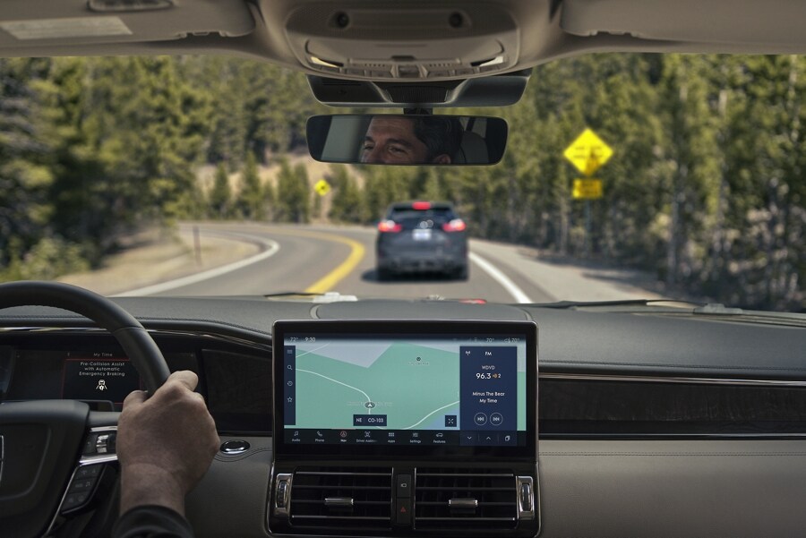 Through the front windshield of a 2023 Lincoln Navigator® SUV a car ahead is shown braking.