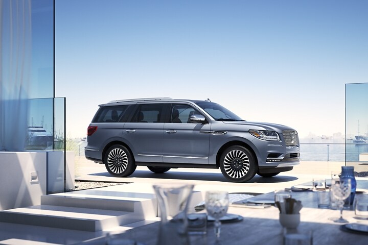 Una SUV Lincoln Navigator® 2023 estacionada cerca del mar muestra el tema Lincoln Black Label Yacht Club.