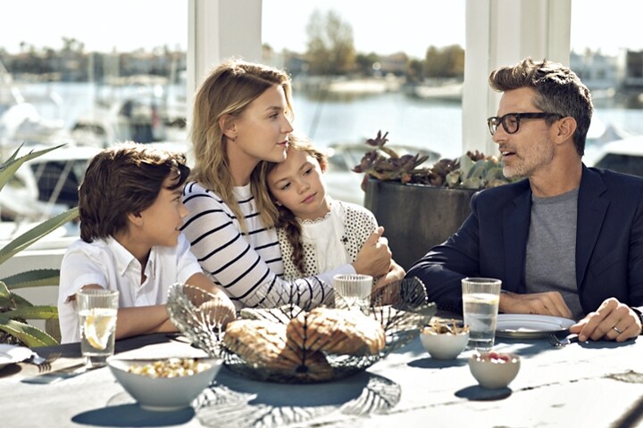 Una familia está disfrutando en un restaurante al aire libre junto al mar.