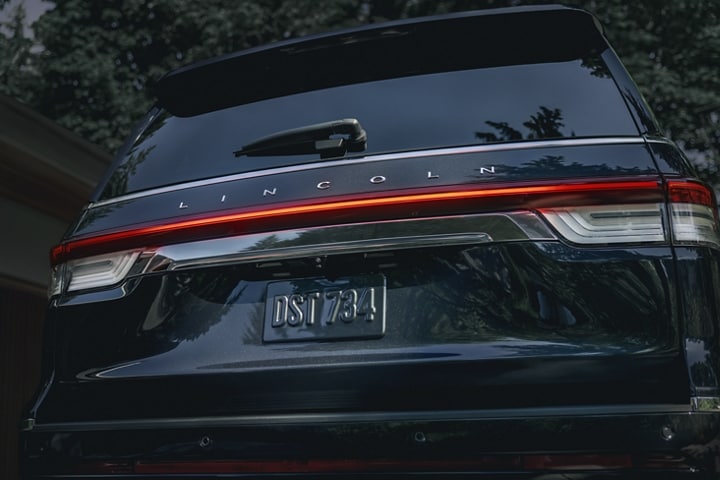 Las luces traseras LED de una SUV Lincoln Reserve Navigator® 2024 iluminan con un resplandor rojo en la noche.