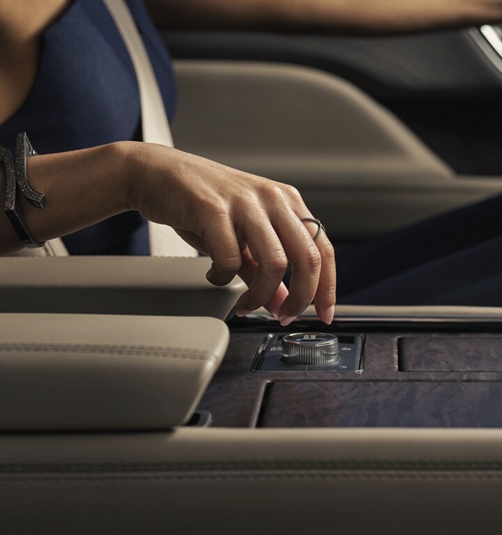 A hand is about to turn the Lincoln Drive Modes knob in the center console.