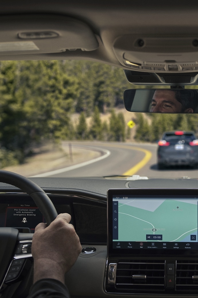Through the windshield we see a vehicle braking ahead as it is driven around a sharp turn on a mountain pass