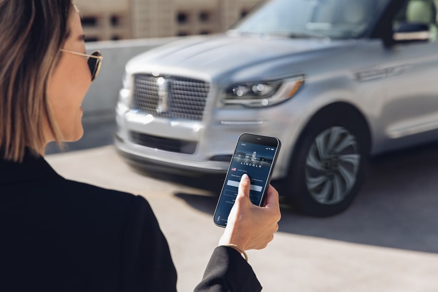 A woman interacts with the Lincoln Way™ App on her smartphone as she approaches her Lincoln.