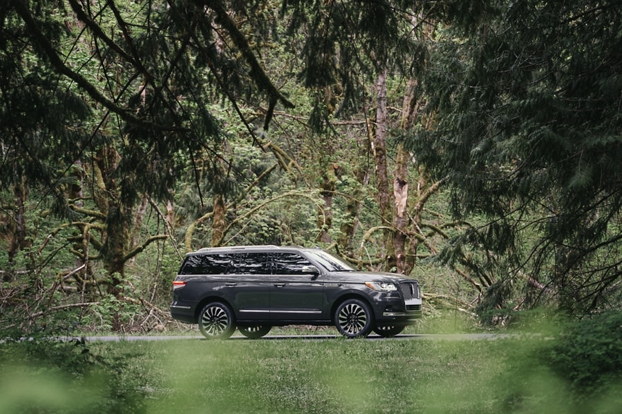 Una Lincoln Navigator® 2024 en un frondoso bosque muestra el diseño exterior del tema Central Park de la Lincoln Black Label.