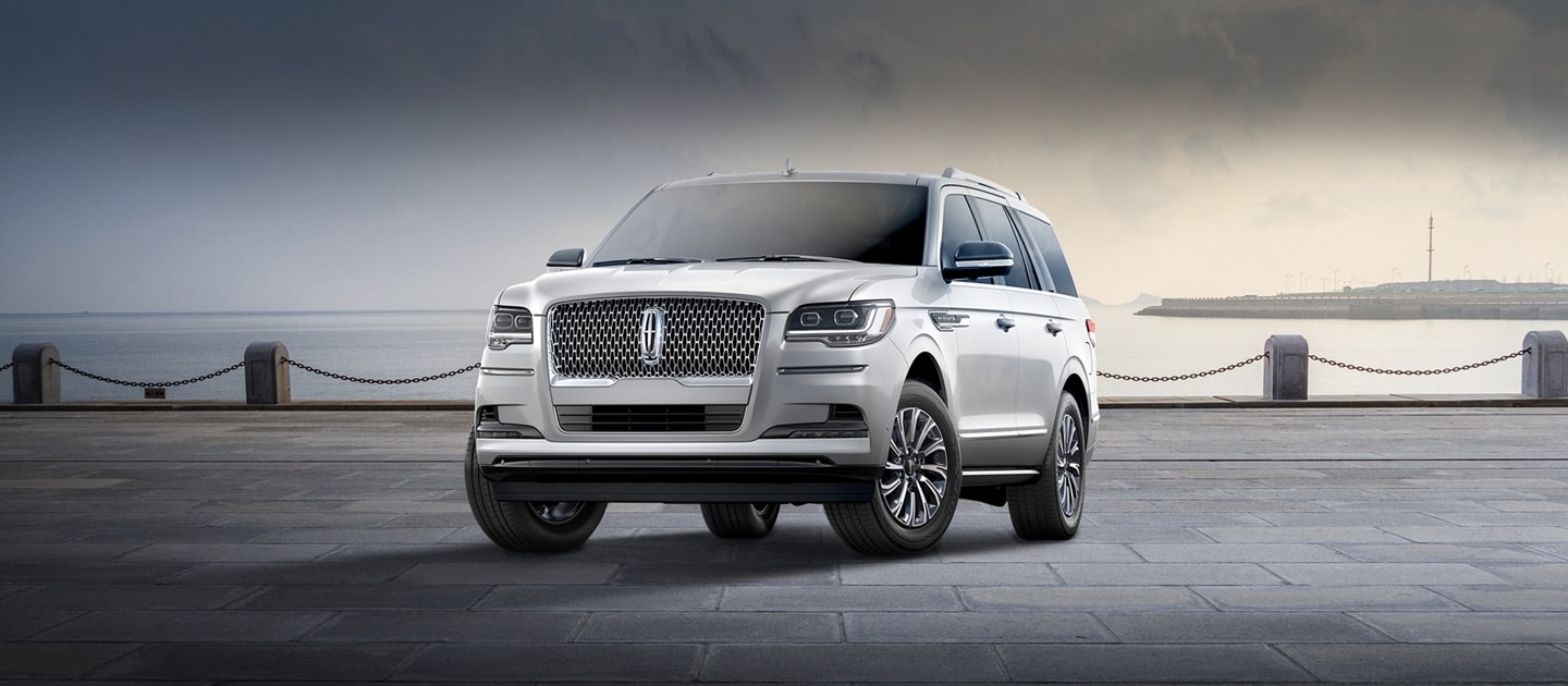 Una SUV Lincoln Navigator® 2024 en plateado radiante estacionada cerca de una bahía bajo un cielo nublado.