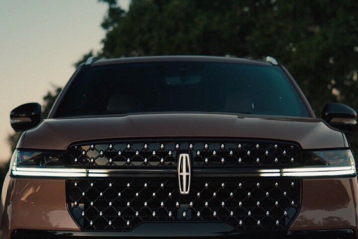 The grille of a parked 2025 Lincoln Navigator® SUV displays the lighting sequence of the Lincoln Embrace